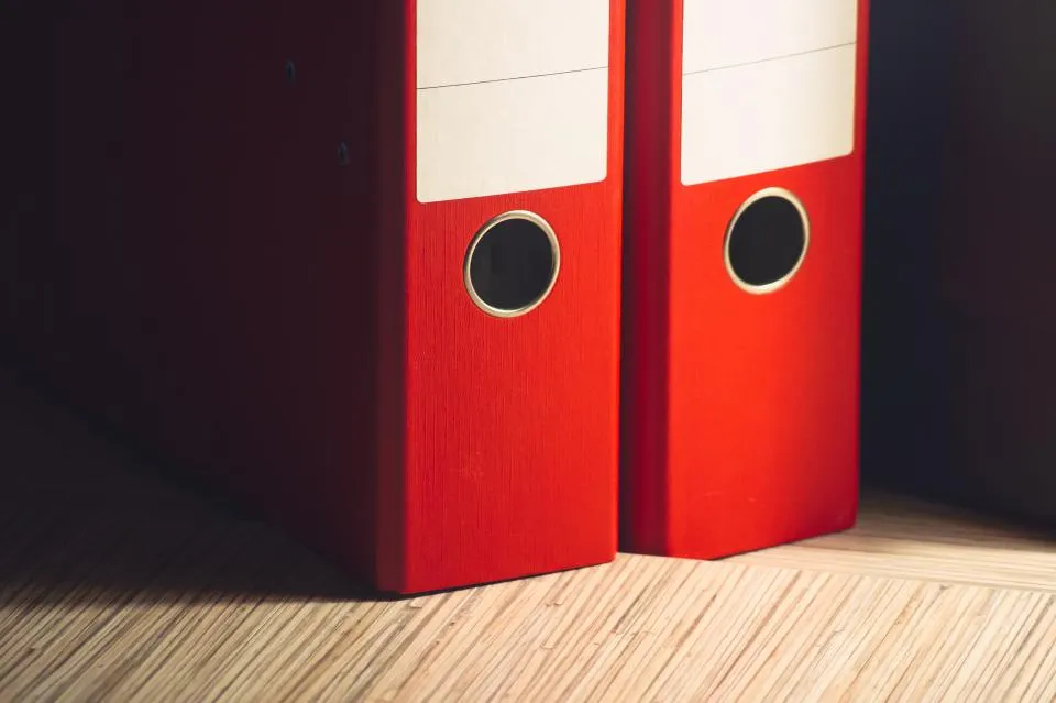 Red ring binders standing on a wooden desk