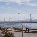 Wind turbines and solar panels under a clear sky, representing sustainable business technology